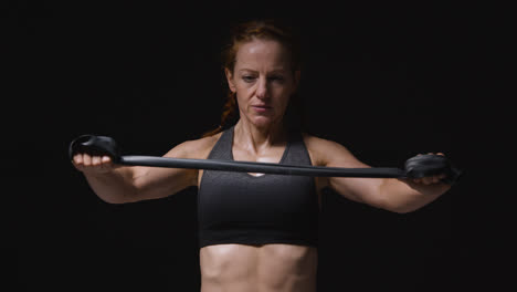 Studio-Shot-Of-Mature-Woman-Wearing-Gym-Fitness-Clothing-Exercising-With-Resistance-Band